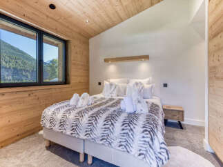 Experience ultimate comfort in this charming bedroom featuring a luxurious king-size bed adorned with a plush, patterned duvet and soft white linens.