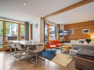 Experience mountain living in this charming apartment featuring a spacious dining area with large windows offering scenic views.