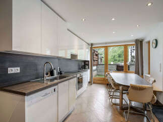 Experience modern living in this stunning kitchen and dining area, featuring sleek white cabinetry and a dark wood backsplash.