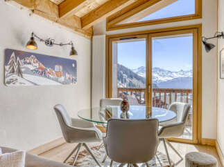 Experience breathtaking mountain views from this dining area, featuring a sleek glass-top table surrounded by comfortable chairs.
