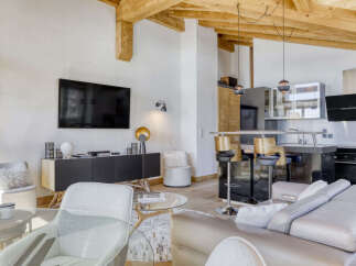 Experience modern alpine living in this stunning open-plan apartment, featuring exposed wooden beams and a sleek, contemporary kitchen island with bar stools.