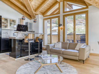 Experience modern alpine living in this stunning apartment, featuring a sleek black kitchen island with bar stools and a comfortable leather sofa.