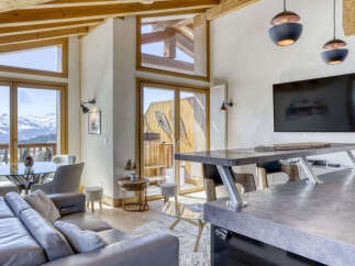 Experience breathtaking mountain views from this stunning living space, featuring a modern open-plan design with a sleek kitchen island and comfortable seating.