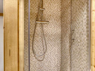Experience a refreshing shower in this modern bathroom featuring a stylish shower enclosure with a sleek chrome showerhead and hose.