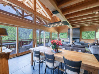 Experience luxurious mountain living in this stunning chalet, featuring a grand dining area with a large wooden table perfect for gatherings.