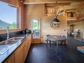 Experience rustic charm in this stunning log cabin kitchen, featuring a large window with breathtaking mountain views.