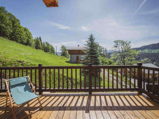 Enjoy breathtaking mountain views from this charming wooden deck, complete with a comfortable lounge chair perfect for soaking up the sun.