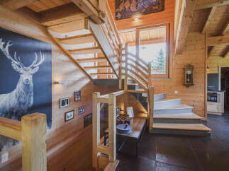 Experience rustic charm in this stunning log cabin featuring a grand wooden staircase and a striking deer mural.