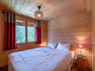 Experience cozy mountain living in this charming wooden bedroom, featuring a comfortable queen-size bed adorned with crisp white linens and decorative pillows.