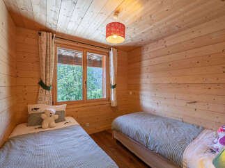Experience cozy mountain living in this charming wooden bedroom, featuring two comfortable twin beds perfect for guests or family.