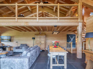 Experience rustic luxury in this stunning log cabin living space, featuring a spacious open-plan design with exposed wooden beams and a cozy loft area.