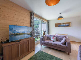 Experience cozy living in this charming apartment featuring a spacious living area with a large flat-screen TV and comfortable seating.