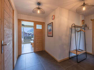 Step into this charming entryway featuring warm wooden doors and floors, complemented by stylish industrial pendant lighting.
