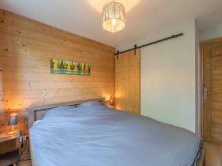 Experience cozy mountain living in this charming bedroom featuring warm wood-paneled walls and a comfortable bed.