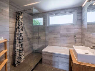 Experience modern comfort in this sleek bathroom featuring a spacious bathtub and a separate glass-enclosed shower.