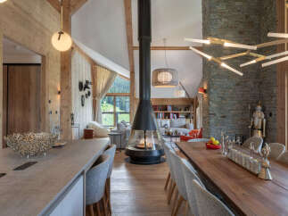 Experience luxury mountain living in this stunning chalet, featuring a modern open-plan living space with a suspended fireplace and a large dining area perfect for gatherings.