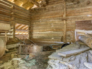 Explore the rustic charm of this historic wooden structure, featuring robust log construction and an open-beam ceiling that hints at its past agricultural use.