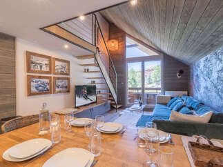 Experience cozy mountain living in this charming apartment, featuring a rustic wooden interior and a modern entertainment area with a large TV.