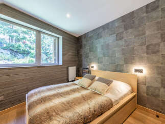Experience cozy mountain living in this charming bedroom featuring a plush, fur-covered bed and a large window offering serene views of nature.