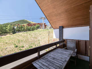 Enjoy breathtaking mountain views from this charming balcony, complete with a rustic wooden table and chairs perfect for al fresco dining.