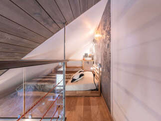 Discover this unique loft bedroom featuring a cozy sleeping area with a plush throw and a minimalist wooden bed frame.