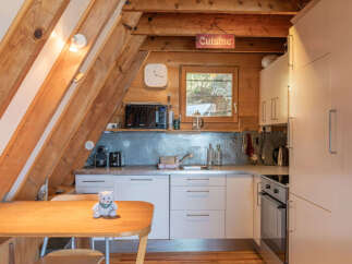 Discover this charming kitchen featuring a cozy dining area with a wooden table and a plush teddy bear.