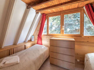Experience cozy living in this charming attic bedroom, featuring a comfortable single bed adorned with a quilted comforter and a neatly folded towel.