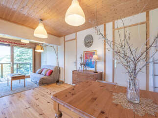 Experience cozy living in this charming mountain retreat, featuring a comfortable sofa bed and a wooden dining table perfect for intimate meals.