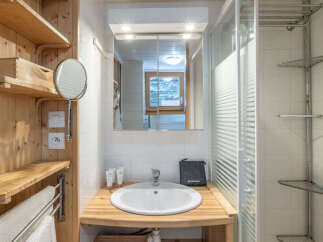 This charming bathroom features a wooden vanity with a white sink and a modern faucet, complemented by a mirrored medicine cabinet.