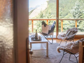 Experience breathtaking mountain views from this stunning living space, featuring a cozy seating area with unique butterfly and wire chairs.
