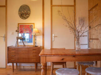 Discover this charming room featuring a vintage wooden dresser adorned with a unique deer sculpture and a colorful framed artwork.
