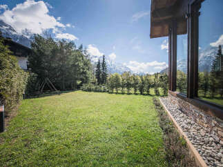 Experience breathtaking mountain views from this stunning property, featuring a lush green lawn perfect for outdoor activities.