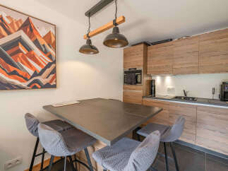 This modern kitchen features a sleek, dark gray dining table with comfortable gray bar stools, perfect for casual meals or entertaining.