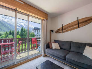 Experience breathtaking mountain views from this charming living space, featuring a comfortable sofa and a unique wooden surfboard wall art.