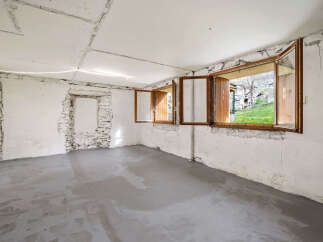 This unfinished room offers a blank canvas for your renovation dreams, featuring exposed stone walls and a newly poured concrete floor.