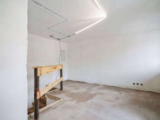 This unfinished interior space features a raw, industrial aesthetic with exposed wooden beams and a concrete floor, perfect for a custom renovation.