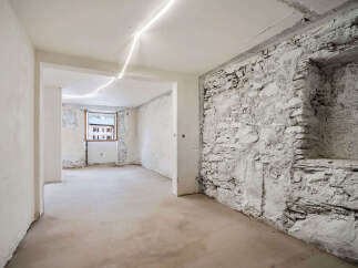 Discover the potential of this unfinished space, featuring a rustic exposed stone wall and a bright window overlooking the neighborhood.