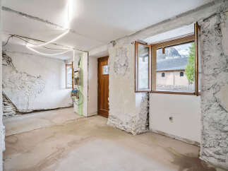 This unfinished interior space offers a blank canvas for renovation, featuring exposed stone walls and a new concrete floor.
