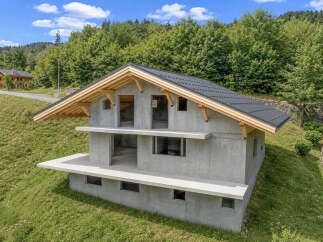 Discover this modern concrete house nestled on a lush green hillside, offering a unique architectural statement.