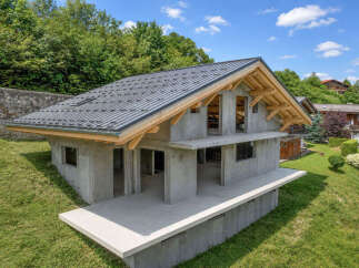 Discover this modern concrete house under construction, nestled on a lush green hillside.
