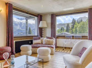 Experience breathtaking mountain views from this cozy living room, featuring plush seating and large windows that frame the stunning alpine scenery.