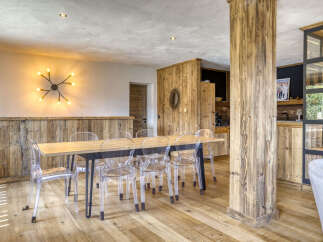 Experience rustic charm in this dining area, featuring a natural wood dining table surrounded by modern transparent chairs.