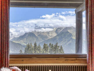 Experience breathtaking mountain views from this stunning property, framed by elegant red curtains.