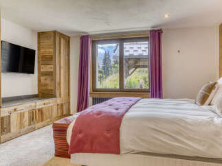Experience mountain living in this charming bedroom featuring rustic wooden cabinetry and a large window with stunning alpine views.