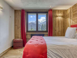 Experience breathtaking mountain views from this charming bedroom, featuring a cozy bed adorned with a vibrant red throw and plush white pillows.