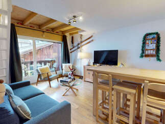 Experience alpine living in this charming apartment, featuring a cozy living area with a plush sofa and a stylish dining bar perfect for après-ski gatherings.