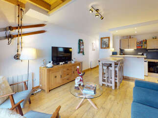 Experience cozy mountain living in this charming apartment, featuring a rustic living area with vintage skis and a modern open-plan kitchen perfect for entertaining.