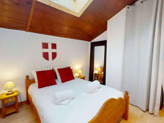 Experience cozy mountain living in this charming bedroom, featuring a comfortable wooden bed adorned with plush red pillows and crisp white linens.