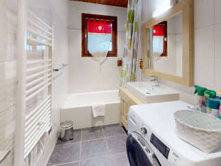 This charming bathroom features a full bathtub, a sink with a wooden vanity, and a convenient washing machine.