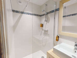 Experience modern comfort in this well-appointed bathroom featuring a spacious walk-in shower with a sleek chrome showerhead and a convenient wall-mounted dispenser.